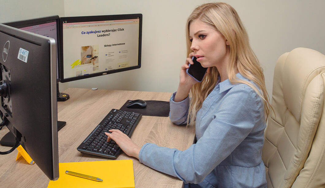A photo of an e-commerce agency employee - Julia Lach, talking to a client on the phone in an office room